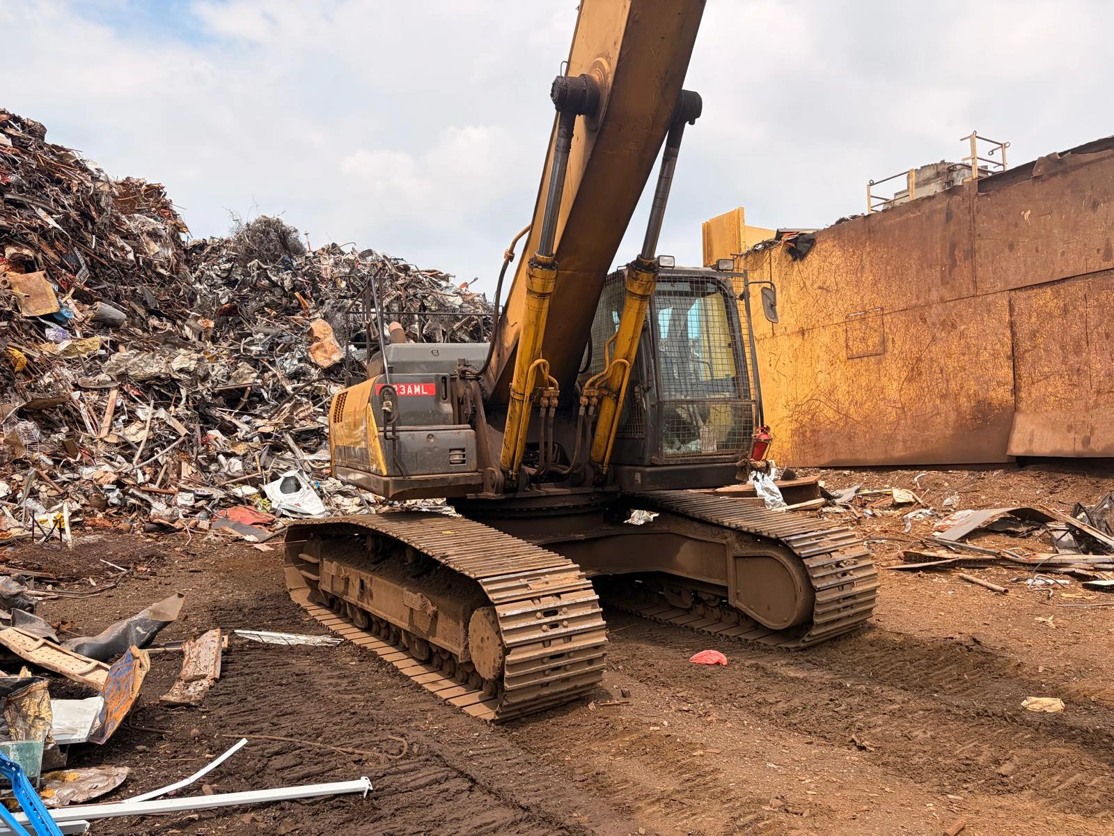 Heavy excavator beside recovered metal and dismantled industrial structures
